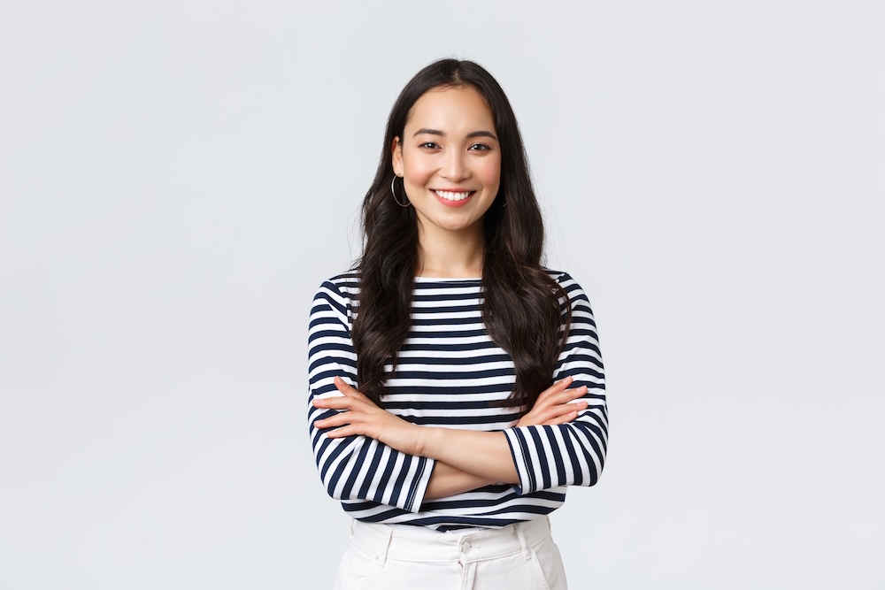 lifestyle, people emotions and casual concept. confident nice smiling asian woman cross arms chest confident, ready to help, listening to coworkers, taking part conversation